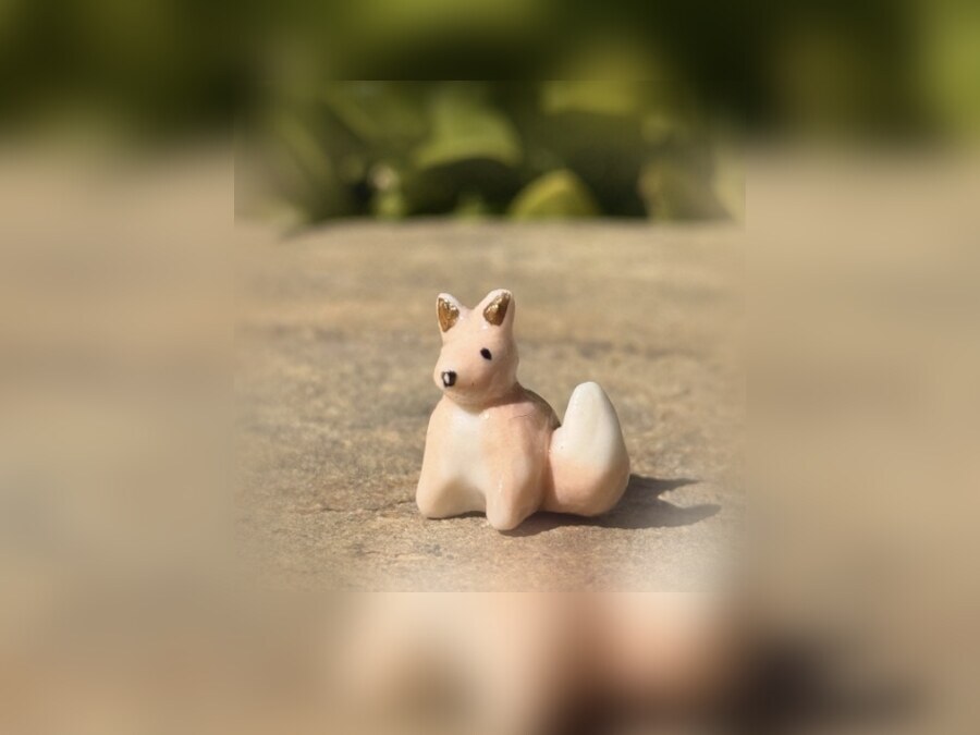 Petites figurines de renard en porcelaine blanche, faites main, posées dans l'herbe