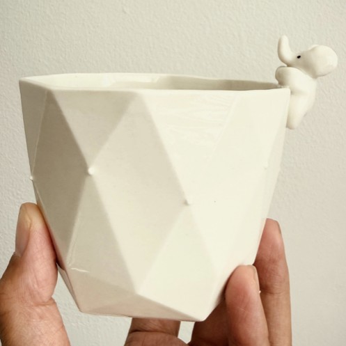 Tasse de naissance en porcelaine facettée tenue en main, ornée d'une figurine éléphant et d'une touche d'or