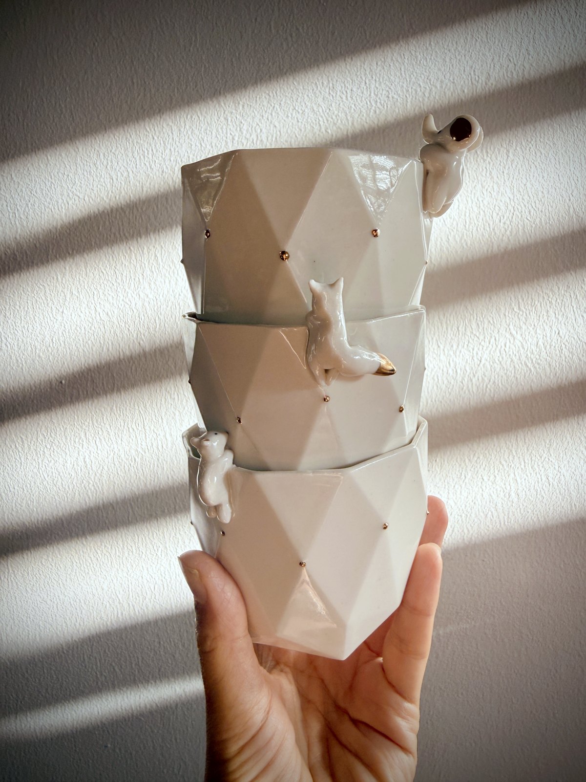 Tasses en porcelaine empilées, ornées de figurines animales et de pois d'or, baignées d'une lumière rasante