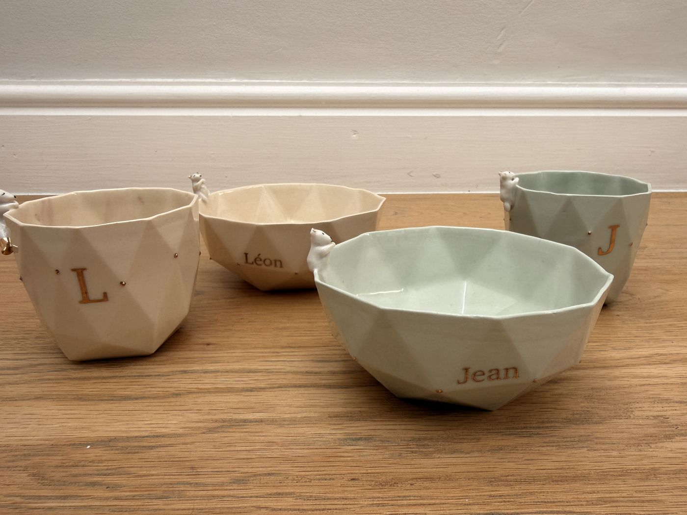 Bols et timbales facettés en porcelaine céladon et crème, aux prénoms Jean et Léon, chacun avec son ourson